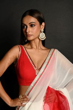 Embrace elegance with our Red and White Hand Embroidered Ruffle Saree in georgette-organza. Featuring intricate embroidery and a chic ruffle design, this set includes a stylish stitched blouse. Perfect for weddings and special occasions, it effortlessly combines classic charm with modern sophistication. Elegant Georgette V-neck Blouse, Elegant V-neck Georgette Blouse, Georgette Blouse Piece V-neck For Designer Wear, V-neck Georgette Blouse For Reception, Wedding Blouse Piece With Ruffles, Traditional Georgette Saree With V-neck, Red Traditional Blouse With Sheer Dupatta, Festive Georgette V-neck Blouse Piece, Fitted Red Blouse With Sheer Dupatta