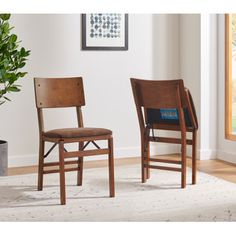 two wooden chairs sitting side by side in front of a potted plant on the floor