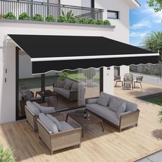 an outdoor living area with couches, tables and chairs under a black awning