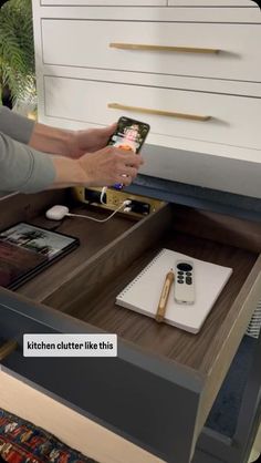 a person holding a smart phone in front of a drawer with other items on it