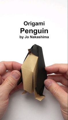 two hands are holding an origami penguin by jo naakshina, which is folded in brown paper