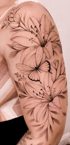 a woman's arm with flowers and butterflies tattooed on the back of her shoulder