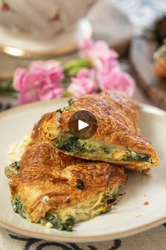 two pieces of omelet on a plate with pink flowers in the back ground