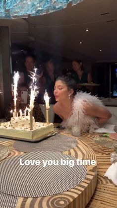 a woman sitting at a table with a cake in front of her and candles on it