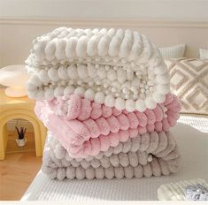 a stack of towels sitting on top of a bed covered in pink and white pom - poms