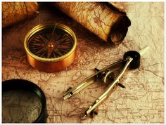 an old map, compass, magnifying glass and other items on it are lying next to each other