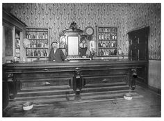 an old black and white photo of a man behind the bar