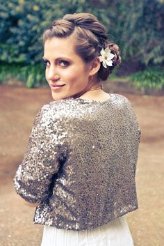 a woman with a flower in her hair wearing a sequin top and white skirt