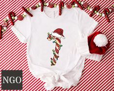 Christmas Candy Cane Tshirt, Candy Cane Crew Shirts, Christmas Matching Shirt, Funny Holiday Tshirt, Family Matching Shirt, Christmas Gifts ---HOW TO ORDER--- 1-) Please, check and review all photos 2-) Choose your t-shirt size and color *Different styles of shirts may have different shades of same color choice due to different manufacturer brands. *For this reason, we recommend you to match shirts from the same styles if you want precisely matching colors (exa. Unisex,V-neck, Tank top, etc.). 3-) Click add to cart. You can go back to add more product 4-)Click "Proceed to check out" 5-)When you check out, you can add a note to seller for any request ---We make DTF printing--- Dtf prints are not only charming and durable, but they also resist fading, cracking, and peeling. With advanced tec White Christmas T-shirt Gift, White Holiday T-shirt Gift, White Holiday Gift T-shirt, White T-shirt For Holiday Gift, White T-shirt As Holiday Gift, Candy Cane Shirt, Christmas Matching, Funny Holiday, Dtf Printing