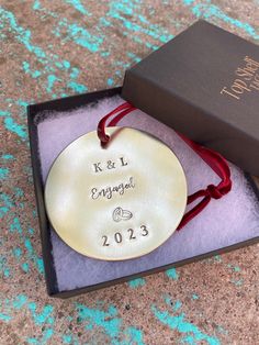 a personalized ornament in a gift box with a red ribbon around it