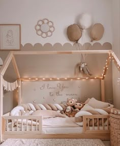 a child's bed with a teddy bear in it and lights strung from the ceiling