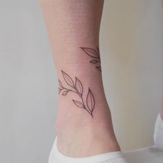 a woman's foot with a small leaf tattoo on the left side of her ankle