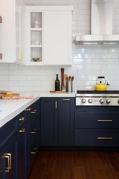 a kitchen with dark blue cabinets and white counter tops, gold pulls on the handles