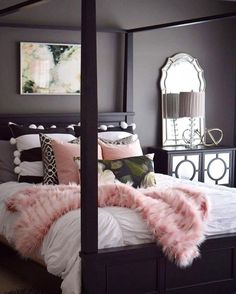 a bedroom with a four poster bed and pink fur throw pillows