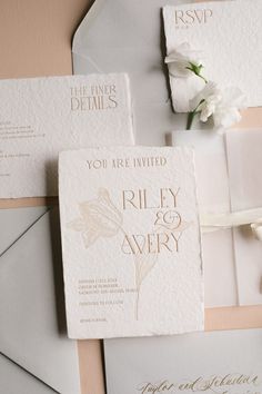 the wedding stationery is laid out on top of an envelope and some flowers are placed next to it