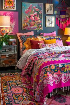 a bed with colorful pillows and blankets on top of it next to a table lamp