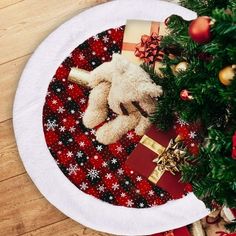 a white teddy bear sitting on top of a table next to a christmas tree