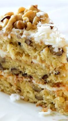 a close up of a piece of cake on a white plate with nuts and icing