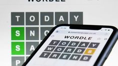 a cell phone with words on the screen next to a keyboard and crossword puzzle