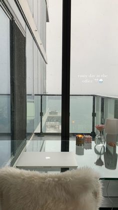 a glass table with a laptop on it in front of a window