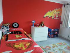 a bedroom decorated in red and yellow with cars bedding