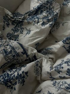 an unmade bed with blue and white comforter on it's side, next to a pillow