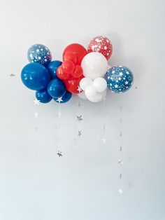 red, white and blue balloons with stars hanging from the ceiling in front of a wall