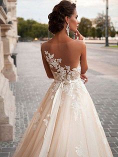 a woman in a wedding dress is standing on the street with her back to the camera