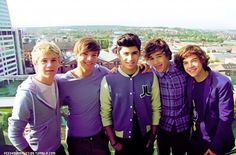 four young men standing next to each other on top of a building