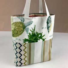 a tote bag with a green turtle and seaweed on the front, sitting on a white surface