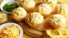 some muffins are sitting on a wooden board next to bowls of cheese and parmesan