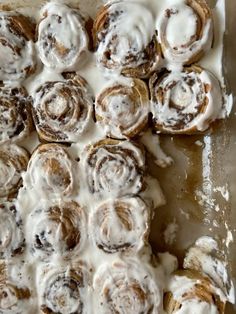 cinnamon rolls with icing sitting on top of a pan