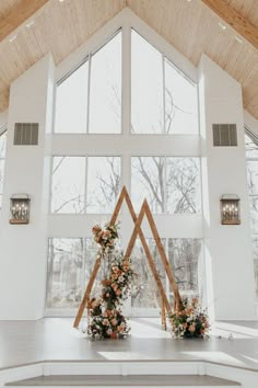 the inside of a church with flowers on the floor and two large windows in it