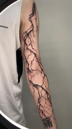 a man's arm with a black and white lightning tattoo on the left forearm