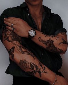 a man with tattoos on his arm and wrist is posing for the camera while wearing a black shirt