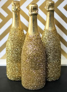 three champagne bottles with gold glitter on them