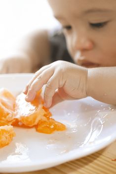 a young child is playing with food on a plate