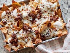 a tray filled with nachos covered in cheese and meat