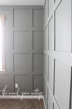 an empty room with gray walls and white trim on the paneling, along with a window in the corner