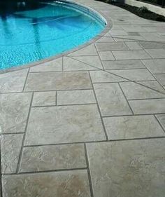 an empty swimming pool in the middle of a patio with stone pavers around it