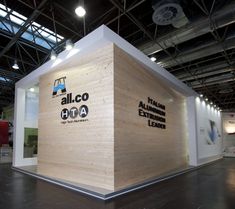 an allco exhibit booth with wooden walls and flooring on the sides, along with lights from overhead overhead