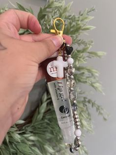 a person is holding a keychain that has a small cross on it and beads