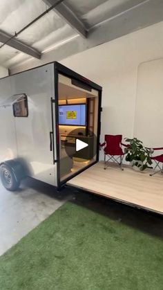 an enclosed trailer is parked in a room with green carpet and grass on the floor