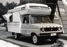 an old camper is parked in front of a large sign that says tarp