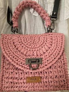 a pink crocheted handbag with a metal buckle on the front and side