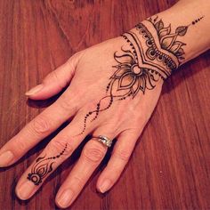 a woman's hand with a henna tattoo on her left arm and wrist