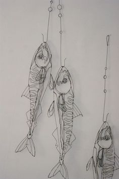 three fish hanging from hooks on a wall next to each other, one being hooked up