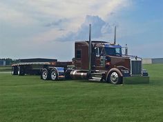 a large semi truck parked on top of a lush green field