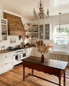 a kitchen with an old fashioned table and chandelier hanging from it's ceiling