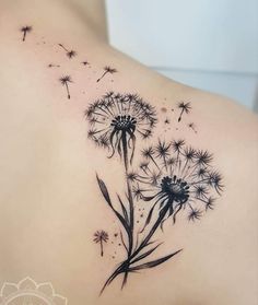 the back of a woman's shoulder with a dandelion tattoo